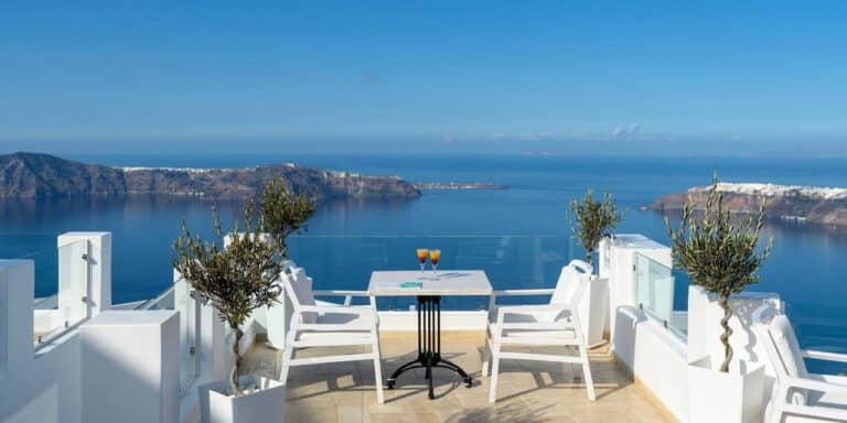 Terrace with a table, chairs and olive trees facing the sea at Above Blue Suites, Imerovigli, Santorini