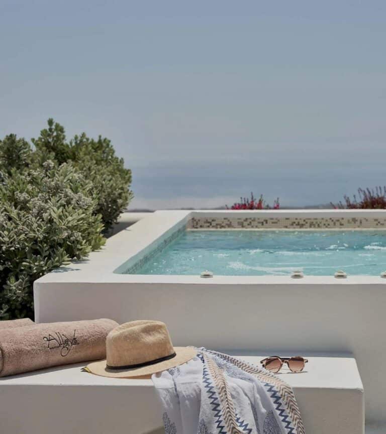 Straw hat and towel beside a terrace pool overlooking the sea at Alleys All-Suite Hotel & Spa, Pyrgos, Santorini