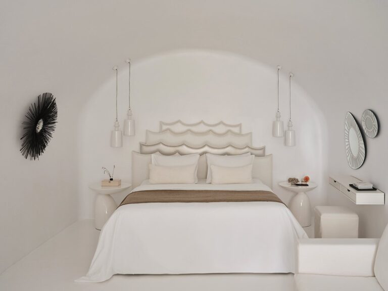 Bedroom with a sculpted headboard under a vaulted ceiling at Canaves Sunday, Oia, Santorini
