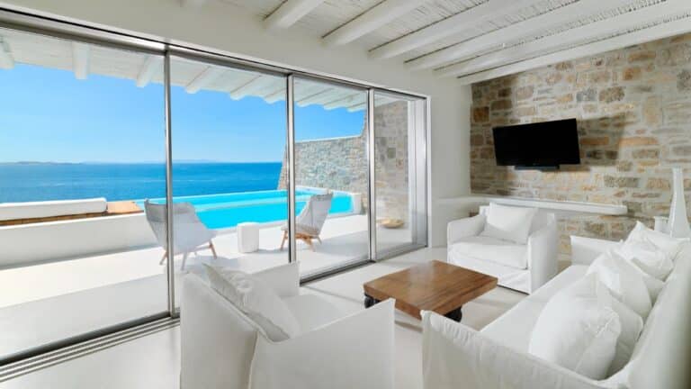 Suite living room with floor-to-ceiling windows and sea views at Cavo Tagoo, Mykonos