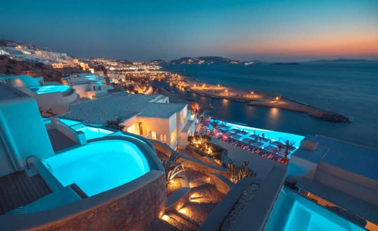 Pools and terraces lit up at dusk above Mykonos Town at Cavo Tagoo, Mykonos