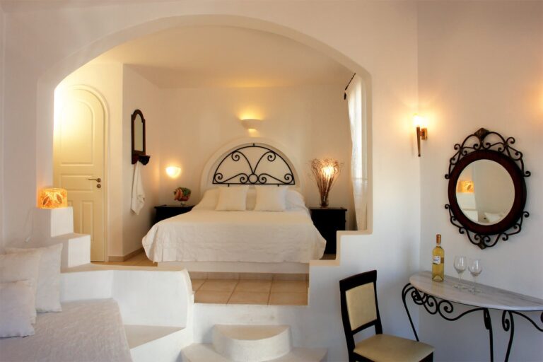 Bedroom with an arched alcove and wrought-iron bed at Chora Resort Hotel & Spa, Folegandros