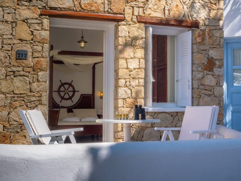 Stone-walled patio with white garden chairs at Chora Resort Hotel & Spa, Folegandros