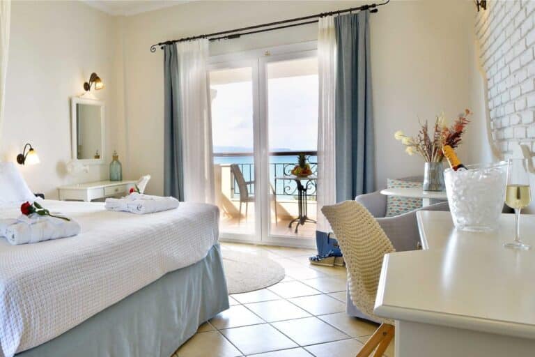 Bedroom with doors opening onto a sea-view balcony at Delfino Blu Wellness Boutique Hotel, Agios Stefanos, Corfu