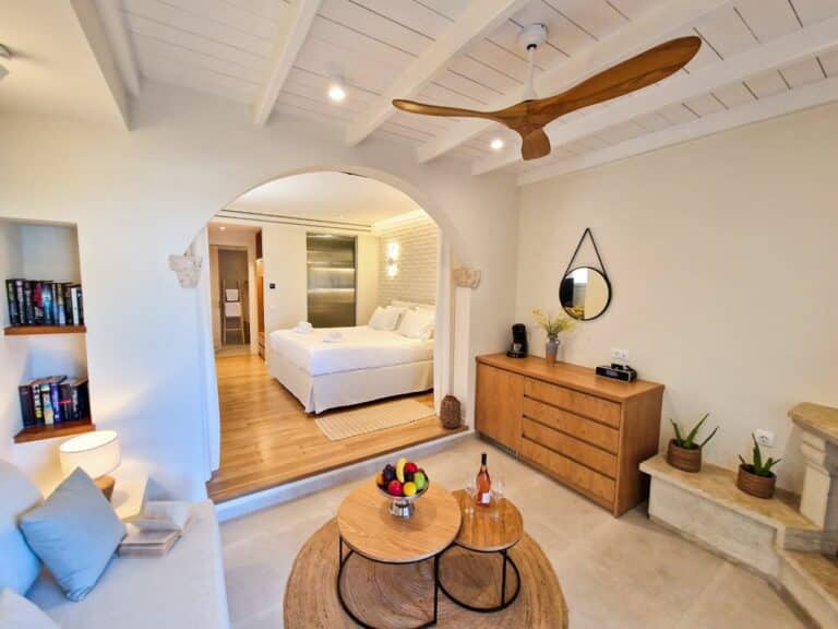 Suite with a lounge and arched doorway to the bedroom at Delfino Blu Wellness Boutique Hotel, Agios Stefanos, Corfu