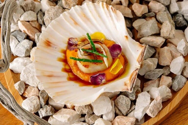 Scallop dish served on a bed of pebbles at Domes White Coast, Mytakas, Milos