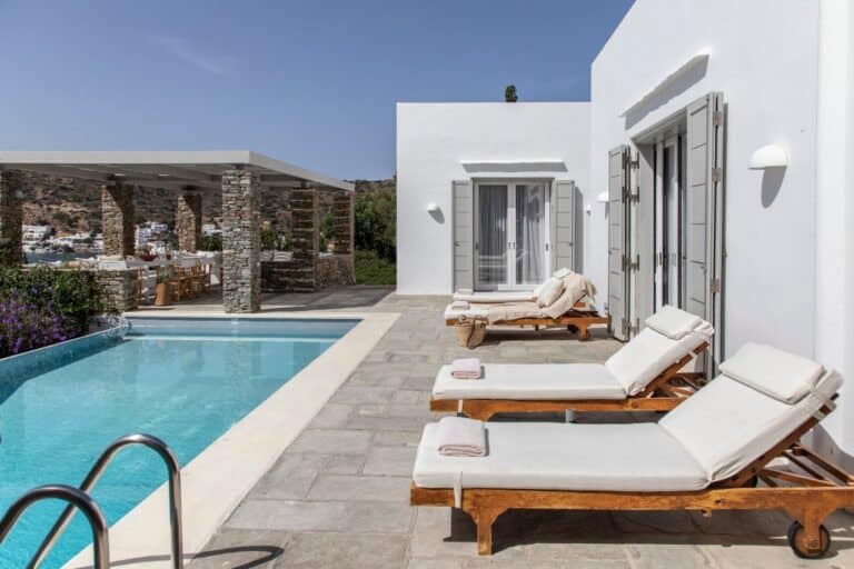 Villa pool lined with wooden sun loungers at Elies Resorts, Vathi, Sifnos