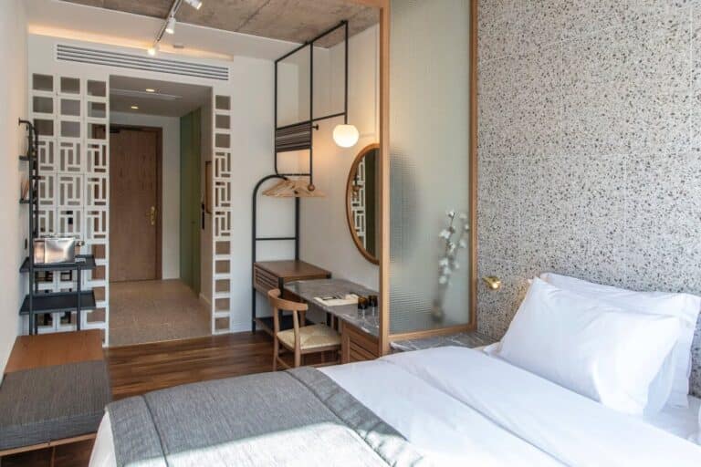Bedroom with a terrazzo wall and crisp white linen at Ergon House, Athens